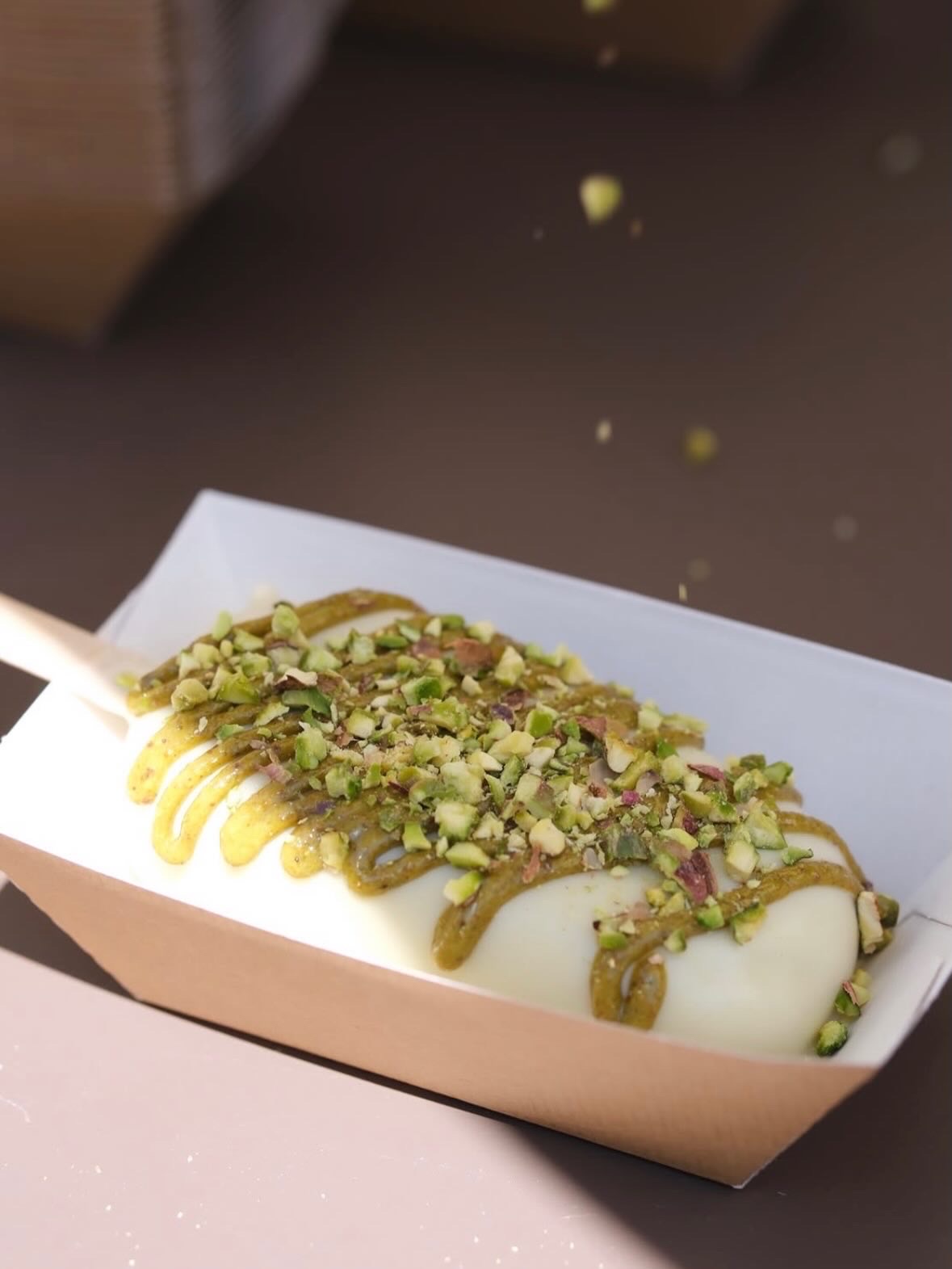 Gros plan sur un bâtonnet glacé pistache et ses éclats, matière et artisanat