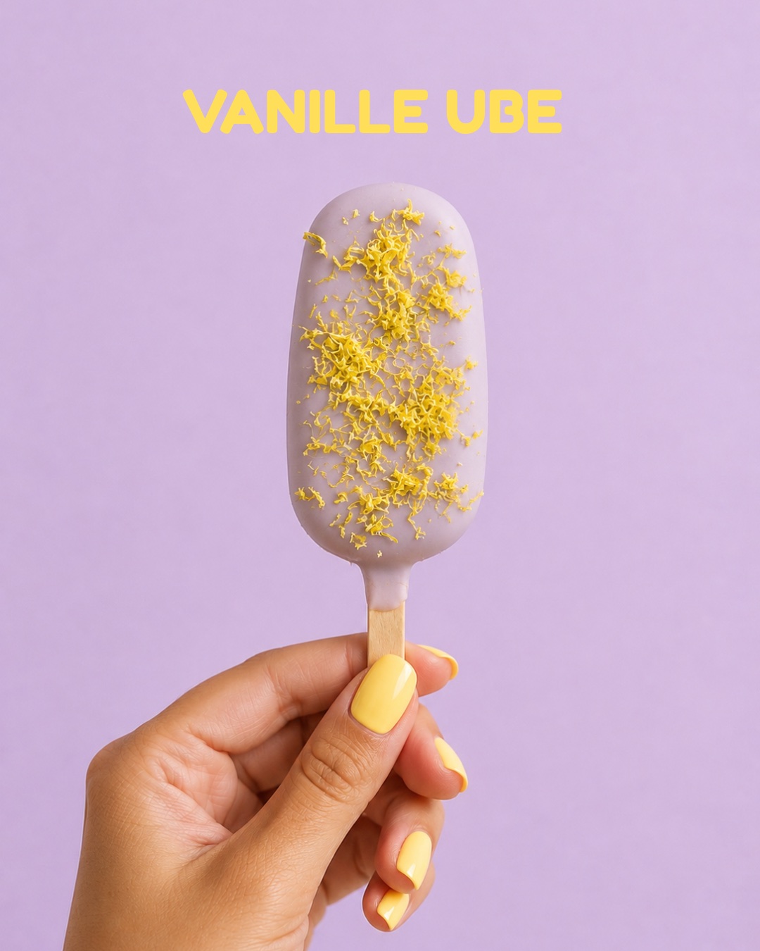 Bâtonnet glacé Vanille Ube au glaçage lilas et zestes dorés, sur fond lilas